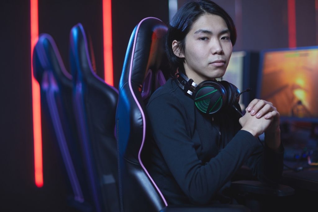 A young male sits at a computer with headphones