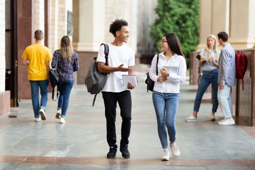 A male and female communications student chat while walking after class