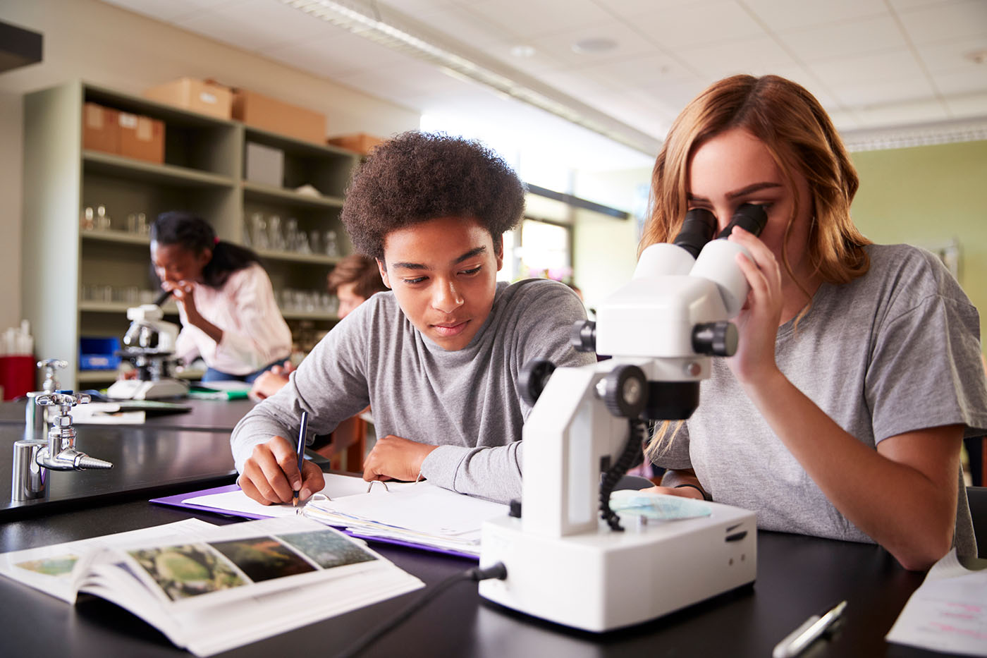 biology students looking through microscope