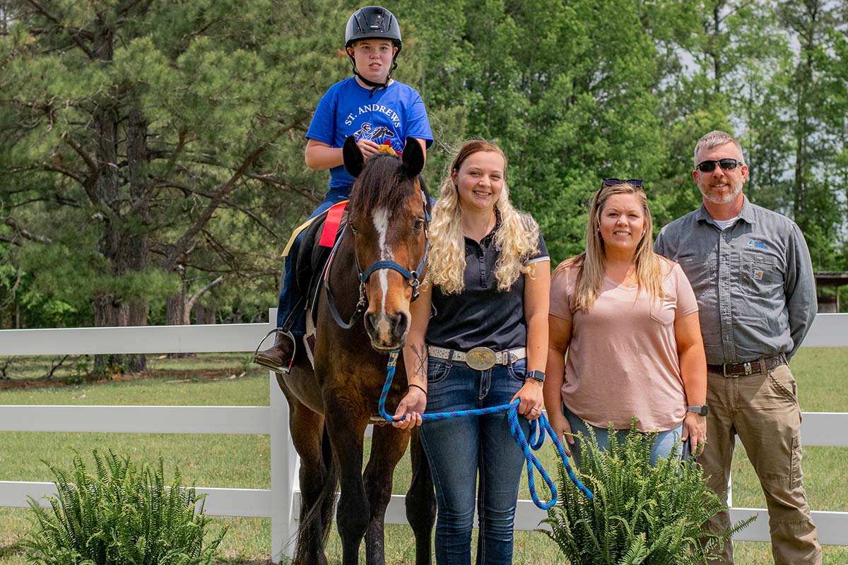 student posing for picture with family and horse