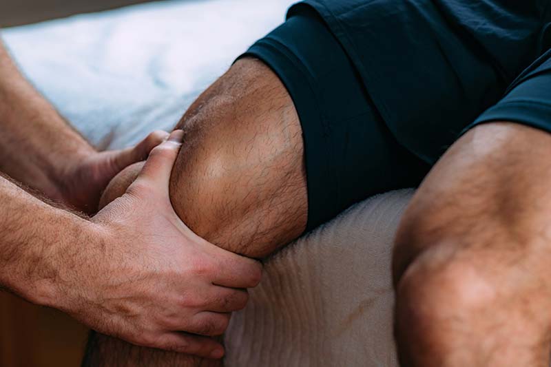 therapist giving knee massage to man