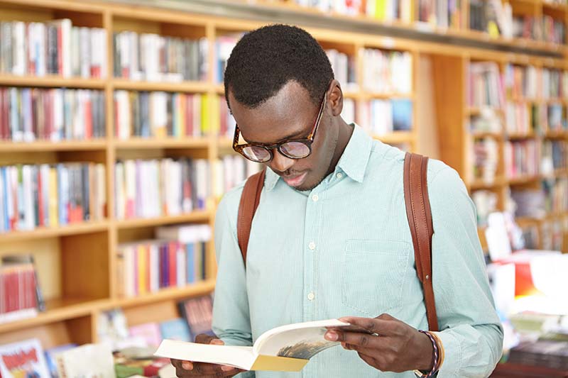 young man looking at book in the library