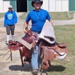 Tyler carrying saddles at equestrian facility