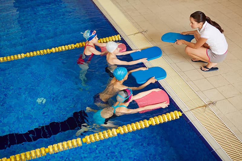 a teacher instructs children in a swim class