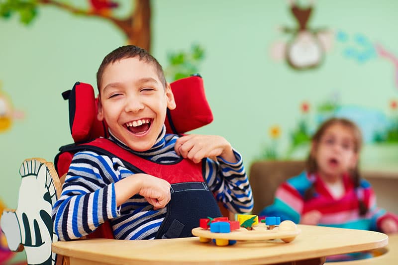 Special education student in motorized chair smiling in classroom