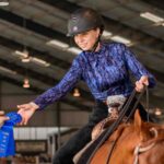 woman riding horse collecting prize